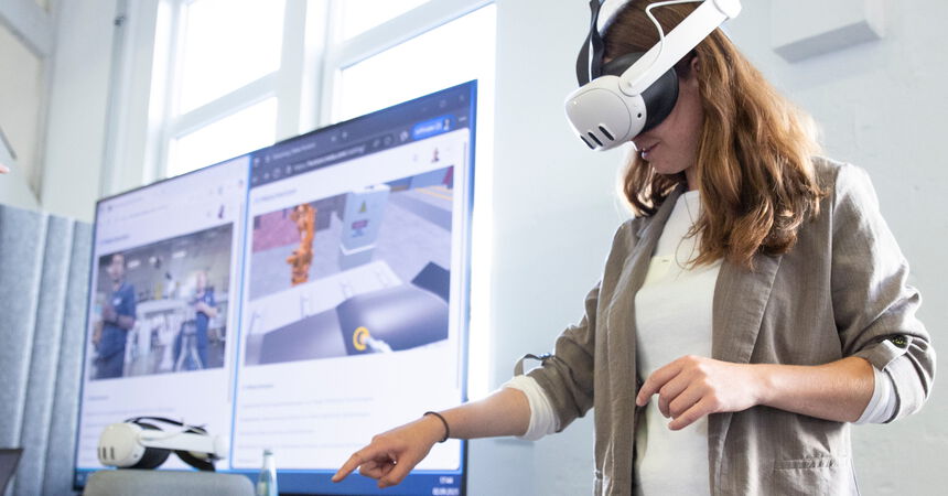 Person nutzt eine VR-Brille, um eine virtuelle Arbeits- und Produktionsumgebung zu erkunden.