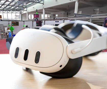 VR-Brille vor einer virtuellen Produktionsumgebung zur Simulation und Gestaltung von Arbeits- und Fertigungsprozessen.